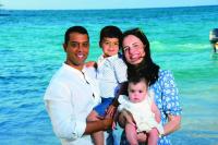 A family poses for a photo together on a beach with the ocean behind them